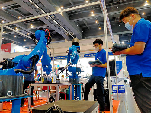 兩位技術人員各自操作一台機器人，合力焊接一個工件